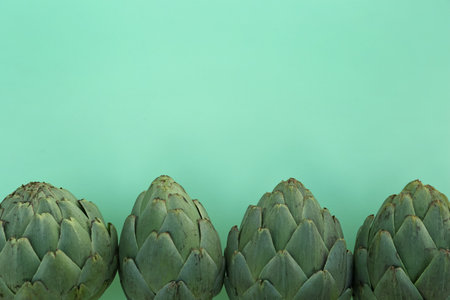 Whole fresh raw artichokes on green background, flat lay. Space for textの写真素材