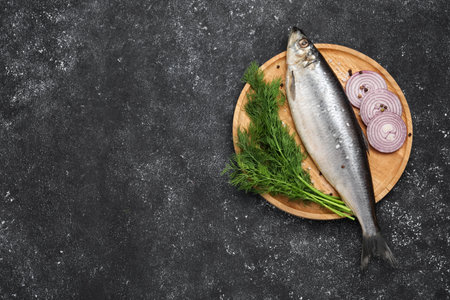 Delicious salted herring, dill and onion on dark gray table, top view. Space for text