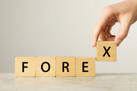 Woman making word Forex with wooden cubes on light table against white background, closeupの写真素材