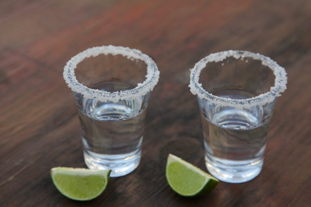 Mexican tequila shots with lime slices and salt on wooden table, closeupの写真素材