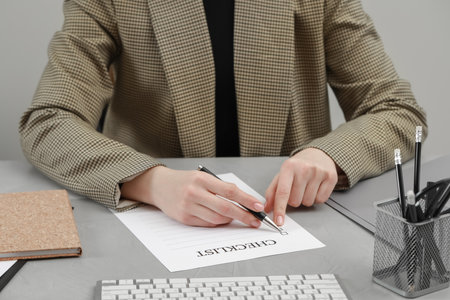 Woman filling Checklist at light gray table, closeupの写真素材