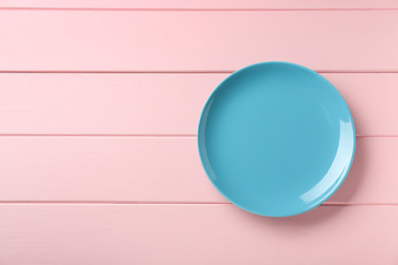 Clean light blue plate on pink wooden table, top view. Space for textの写真素材