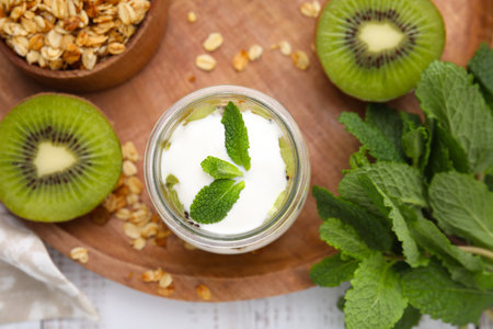 Delicious dessert with kiwi, yogurt and mint on wooden board, flat layの写真素材