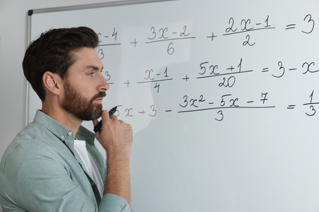 Mature teacher at whiteboard in classroom during math lesson