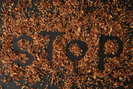 Word Stop made of dry tobacco on dark gray background, flat lay. Quitting smoking concept