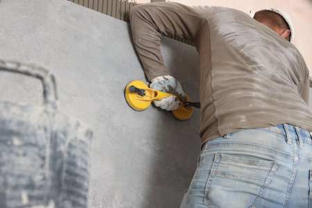 Worker installing wall tile with vacuum holder indoors, closeupの写真素材