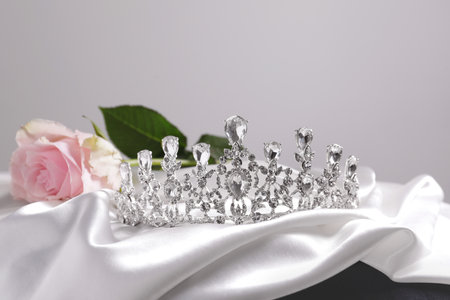 Beautiful silver tiara with diamonds and roses on white silk clothの写真素材