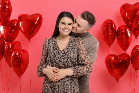 Lovely couple near heart shaped air balloons on red background. Valentine's day celebrationの写真素材
