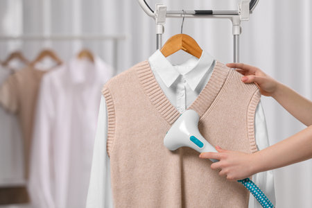 Woman steaming clothes on hanger at home, closeupの写真素材