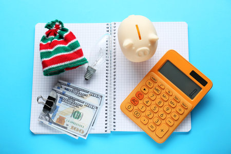 Flat lay composition with piggy bank and calculator on light blue background. Paying bills conceptの写真素材