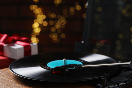 Turntable with vinyl record and Christmas gift boxes against blurred lights, closeupの写真素材