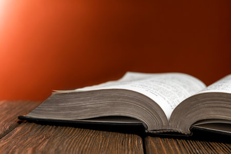 Open Bible on wooden table against brown background, closeup. Space for textの写真素材
