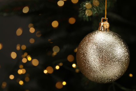 Beautiful Christmas ball hanging on fir tree branch against blurred lights, closeup. Space for textの写真素材