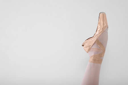 Young ballerina in pointe shoes practicing dance moves on light gray background, closeup. Space for textの写真素材