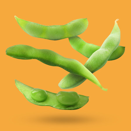 Delicious cooked soy pods falling on orange background. Edamameの写真素材