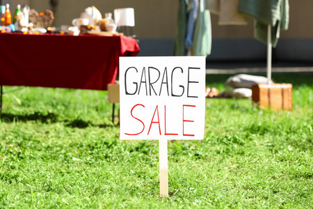 Sign Garage sale written on cardboard in yard