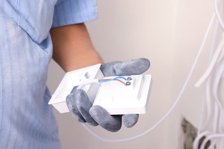 Electrician with remote meter indoors, closeup. Installation of electrical wiringの写真素材