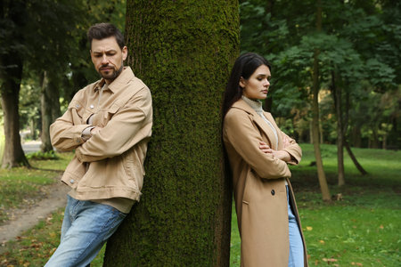 Upset arguing couple near tree in park. Relationship problems