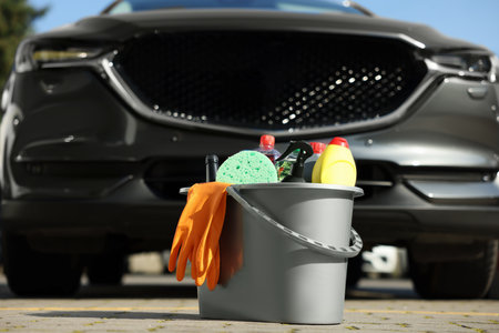 Car cleaning products in bucket near automobile outdoors on sunny dayの写真素材