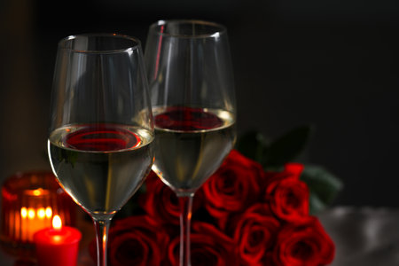 Glasses of white wine, burning candles and rose flowers against blurred background, space for text. romantic atmosphereの写真素材