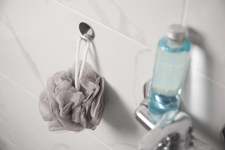 Gray shower puff and bottle of body wash gel in bathroomの写真素材