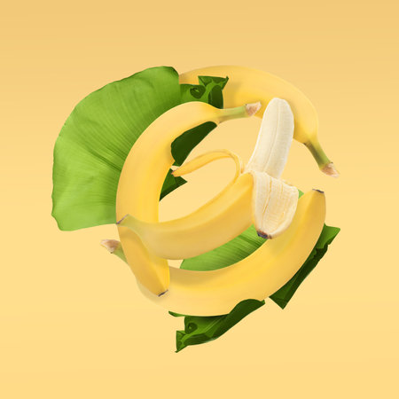 Delicious ripe banana fruits and leaves falling on pale yellow backgroundの写真素材