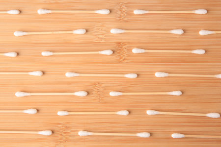 Many clean cotton buds on wooden table, flat lay