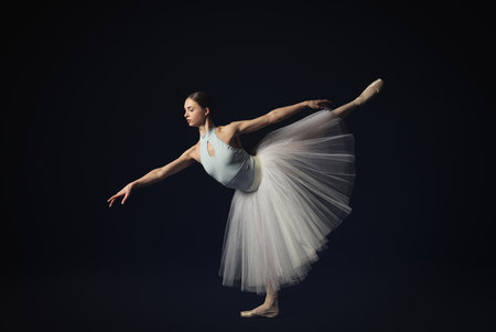 Young ballerina practicing dance moves on black backgroundの写真素材