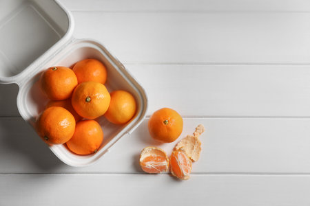 Paper box with fresh ripe tangerines on white wooden table, flat lay. Space for textの写真素材