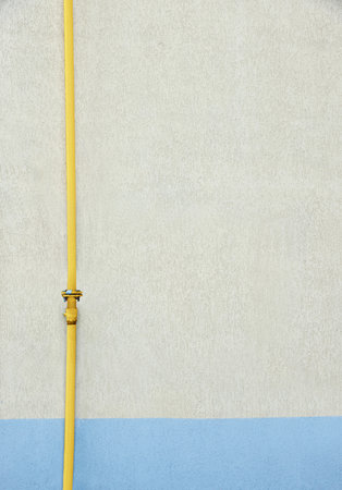 Yellow gas pipe near beige wall outdoors, space for text