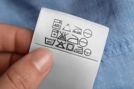 Woman holding clothing label on light blue garment, closeupの写真素材