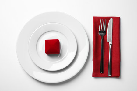 Beautiful table setting with gift box for romantic dinner on white background, flat layの写真素材