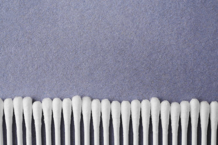 Many clean cotton buds on blue background, flat lay. Space for text