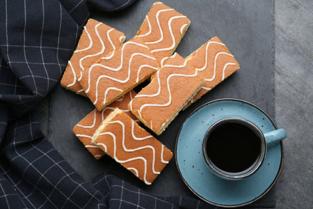 Tasty sponge cakes and hot drink on gray table, flat lay