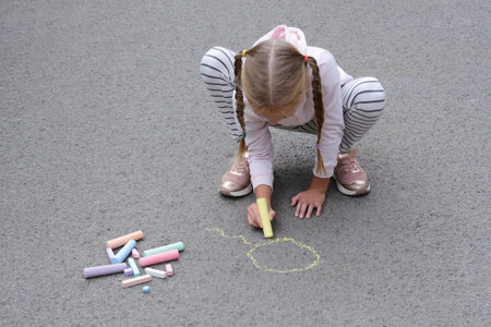 Little child drawing sun with chalk on asphaltの写真素材