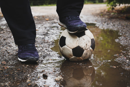 Man with soccer ball in muddy puddle outdoors, closeupの写真素材
