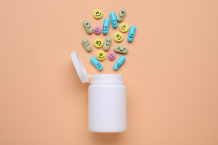 Bottle and antidepressant pills with funny faces on pale orange background, flat layの写真素材