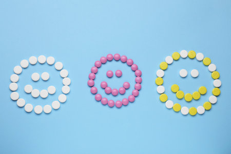 Happy faces made of antidepressant pills on light blue background, flat layの写真素材