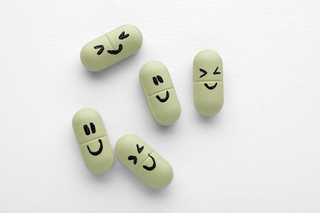 Antidepressant pills with emotional faces on white background, top viewの写真素材