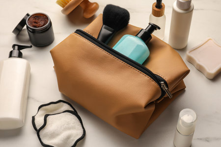 Preparation for spa. Compact toiletry bag and different cosmetic products on white marble tableの写真素材