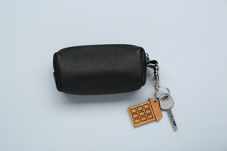 Leather case with key on light gray background, top view