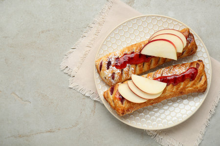 Fresh tasty puff pastry with jam and apples on white textured table, top view. Space for textの写真素材