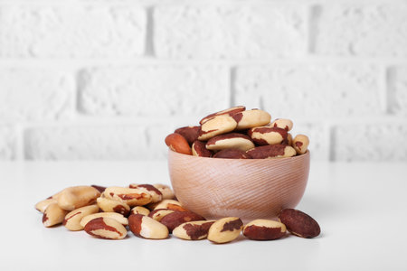 Tasty Brazil nuts on white table against brick wallの写真素材