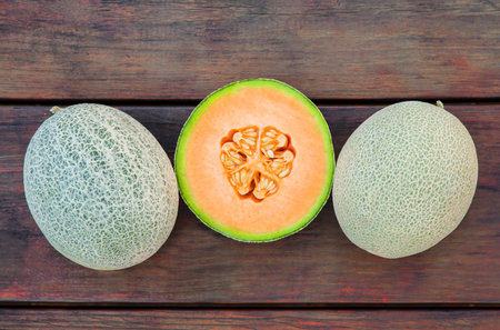 Whole and cut fresh ripe melons on wooden table, flat layの写真素材