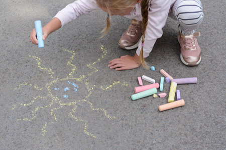 Little child drawing sun with chalk on asphalt, closeupの写真素材