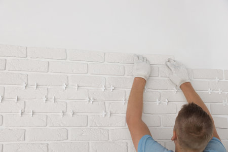 Professional builder installing new white decorative bricks on wall, closeupの写真素材