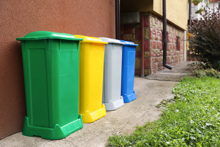 Many colorful recycling bins near brown wall outdoorsの写真素材