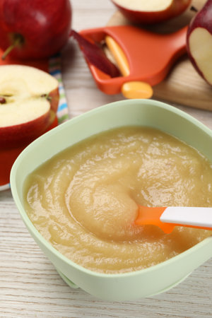 Healthy baby food. Bowl with delicious apple puree and fresh fruits on white wooden tableの写真素材