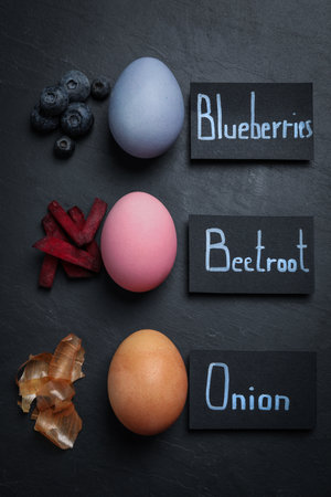Naturally painted Easter eggs on black table, flat lay. Blueberries, beetroot and onion used for...