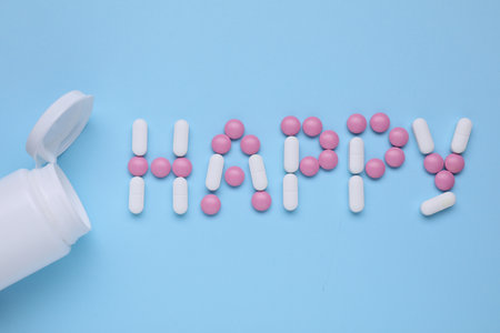 Word Happy made of antidepressants and medical jar on light blue background, flat layの写真素材